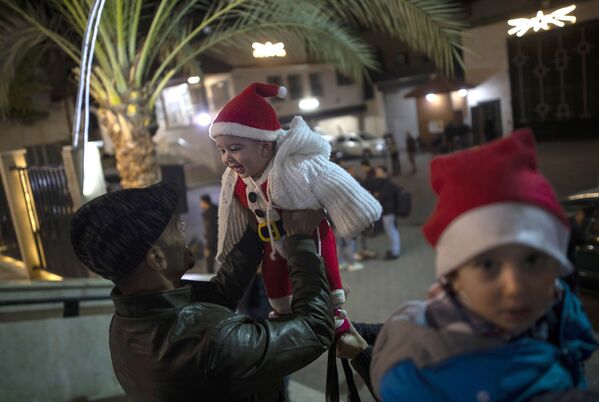 Мужчина играет с ребенком до начала рождественской мессы в Газе  - Sputnik Молдова