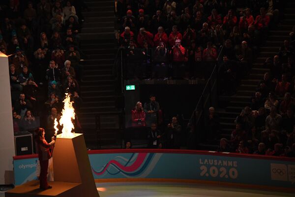 Швейцарская фигуристка Джина Зендер зажигает олимпийский огонь во время церемонии открытия III зимних юношеских Олимпийских игр - Sputnik Молдова