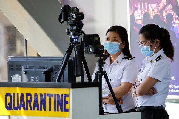 Сотрудники аэропорта в масках следят за тепловым сканером в международном аэропорту Ninoy Aquino на Филиппинах - Sputnik Молдова