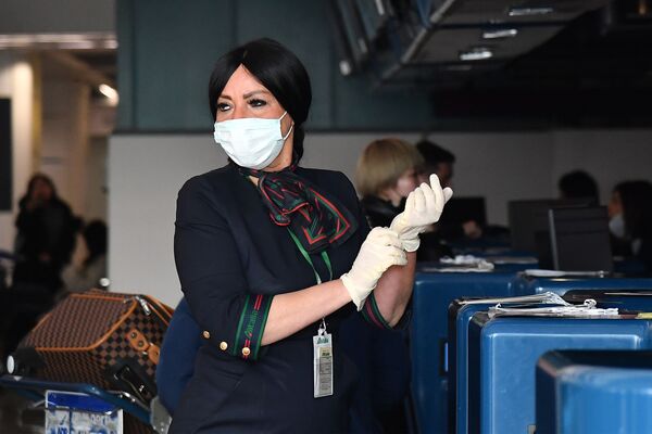  Сотрудница в защитных перчатках и маске при подготовке к регистрации пассажиров у стойки авиакомпании China Southern Airlines в римском аэропорту Фьюмичино  - Sputnik Молдова