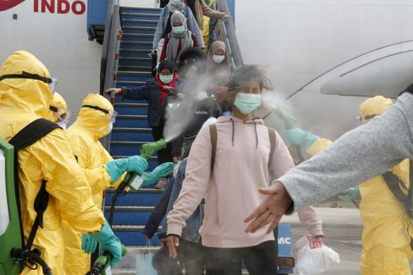 Медики опрыскивают индонезийских граждан антисептиком после прибытия из китайского Уханя, центра эпидемии коронавируса - Sputnik Молдова