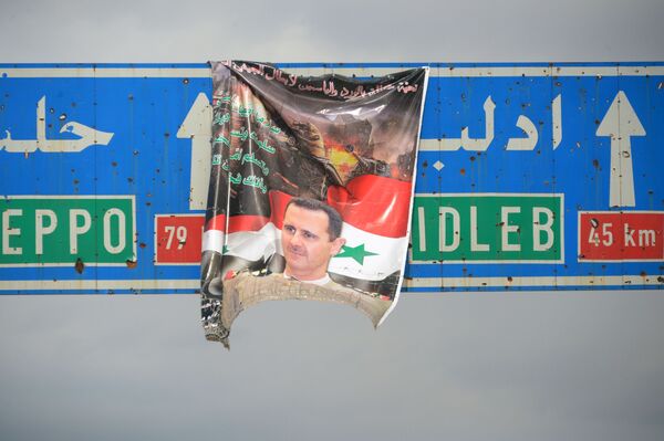 Плакат с портретом президента Сирии Башара Асада на дорожном указателе на город Идлиб в Сирии в окрестностях города Мааррат-эн-Нууман - Sputnik Moldova-România