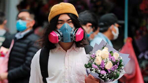 Мужчина в защитной маске и с букетом в День святого Валентина на одной из улиц Гонконга - Sputnik Молдова