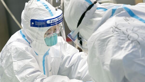 Медицинские работники в защитной одежде у пациента с коронавирусом в больнице Уханьского университета - Sputnik Молдова