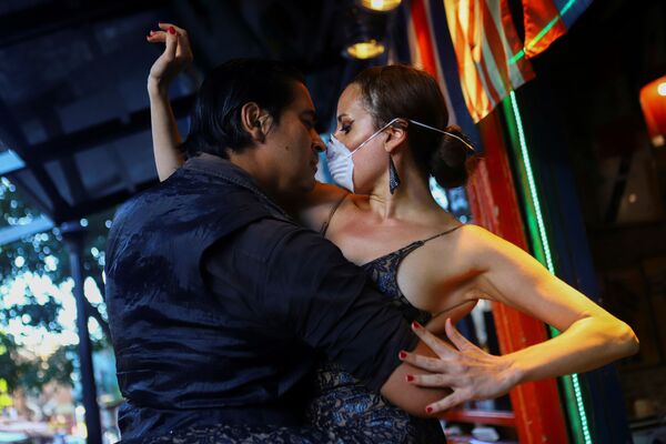 Мужчина и женщина в медицинской маске танцуют танго в почти пустом ресторане в Буэнос-Айресе - Sputnik Молдова