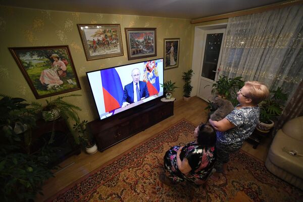 Жители Владивостока во время просмотра трансляции обращения президента России Владимира Путина к гражданам в связи с коронавирусом  - Sputnik Молдова
