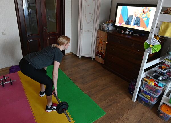 Женщина занимается спортом во время трансляции обращения президента России В. Путина к гражданам из-за ситуации с коронавирусом - Sputnik Молдова