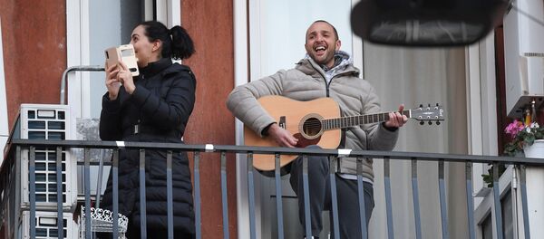 Мужчина с гитарой и женщина со смартфоном на одном из балконов в Милане - Sputnik Moldova