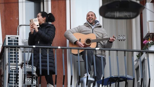 Мужчина с гитарой и женщина со смартфоном на одном из балконов в Милане - Sputnik Moldova