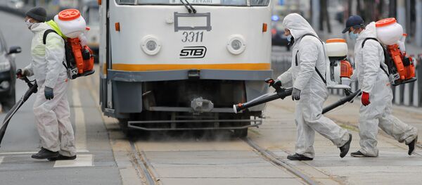 Muncitori pulverizând dezinfectant pe o stradă din București - Sputnik Moldova-România