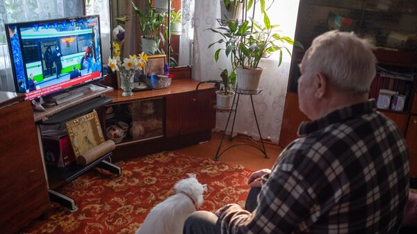 Пожилой мужчина смотрит телевизор у себя дома во время самоизоляции - Sputnik Молдова