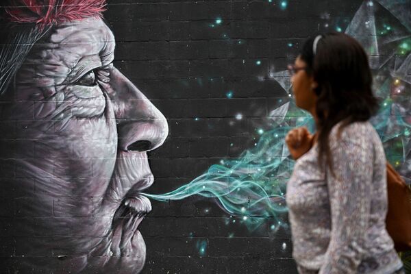 Женщина проходит мимо граффити, нарисованного в рамках фестиваля Graficalia в Кали, Колумбия - Sputnik Молдова