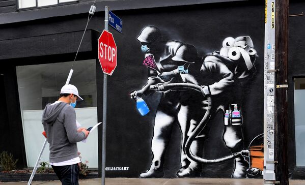Прохожий напротив граффити, посвященного борьбе с коронавирусом, в Лос-Анджелесе - Sputnik Молдова