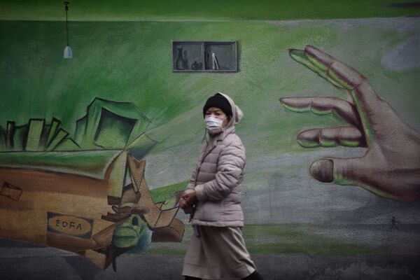 Местная жительница в Ухане, Китай, проходит на фоне стены с граффити - Sputnik Молдова
