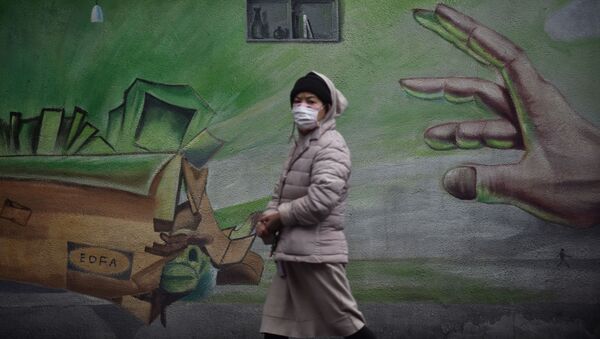 Местная жительница в Ухане, Китай, проходит на фоне стены с граффити - Sputnik Молдова
