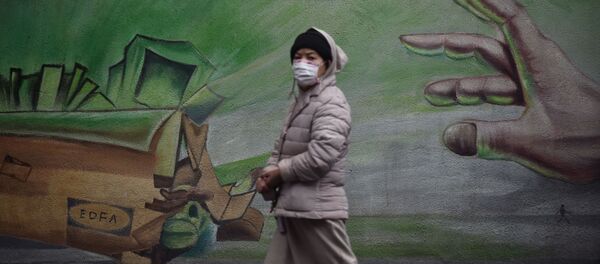 Местная жительница в Ухане, Китай, проходит на фоне стены с граффити - Sputnik Молдова