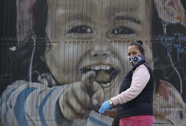 Женщина в защитной маске и перчатках проходит мимо настенной росписи в Соача на окраине Боготы, Колумбия - Sputnik Молдова