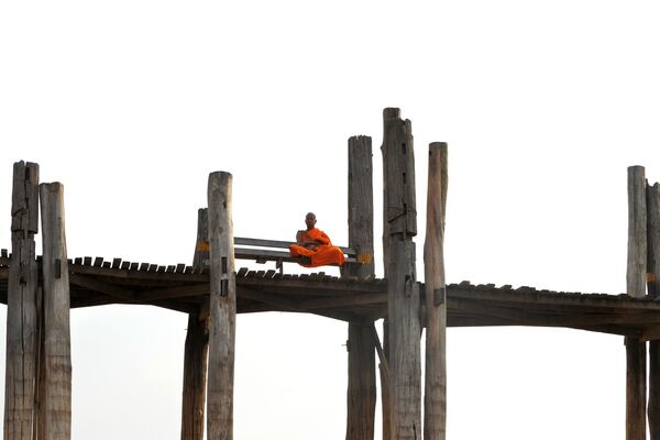 Монах, сидящий на деревянном мосту Убэйн в Амарапуре, округ Мандалай, Мьянма - Sputnik Молдова