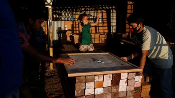 Маленькая девочка болеет за отца, играющего в карром в мебельной мастерской в Лалитпур, Непал - Sputnik Молдова