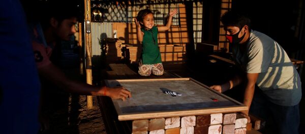 Маленькая девочка болеет за отца, играющего в карром в мебельной мастерской в Лалитпур, Непал Маленькая девочка болеет за отца, играющего в карром в мебельной мастерской в Лалитпур, Непал - Sputnik Moldova-România