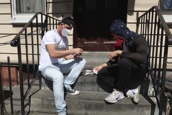 Двое мужчин в защитных масках играют в карты на крыльце дома в Бруклине, Нью-Йорк - Sputnik Молдова