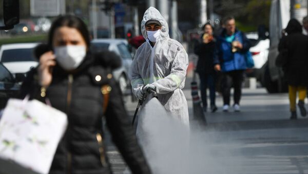 Un muncitor pulverizează dezinfectant pe trotuar - Sputnik Moldova