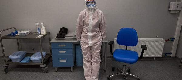 Медицинский работник в защитном снаряжении стоит рядом со сканером компьютерной томографии - Sputnik Moldova