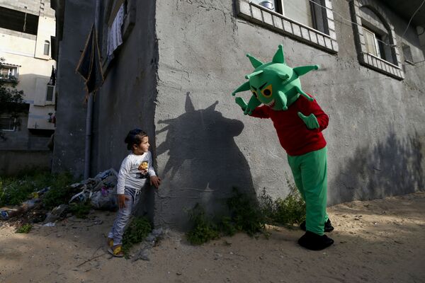 Палестинец в костюме коронавируса играет с девочкой в ​​центральной части Сектора Газа во время пандемии COVID-19 - Sputnik Молдова