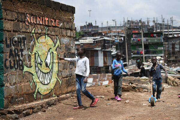 Подростки около граффити, предупреждающем людей о риске возникновения коронавируса COVID-19, в трущобах Найроби, Кения - Sputnik Молдова