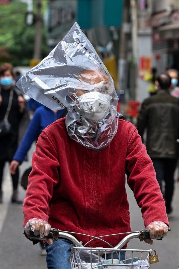 Велосипедист в защитной маске и с пластиковым пакетом на голове на одной из улиц Уханя, Китай - Sputnik Moldova