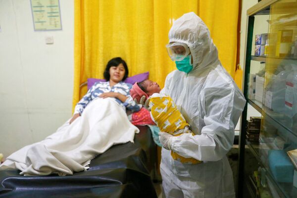  Медсестра в защитном костюме держит новорожденного в родильном отделении в Депоке, недалеко от Джакарты, Индонезия - Sputnik Moldova-România