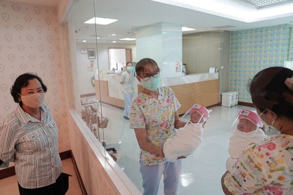 Медсестры в защитных лицевых масках держат новорожденных в защитных лицевых щитках в целях профилактики коронавируса в больнице в Бангкоке, Таиланд - Sputnik Moldova-România