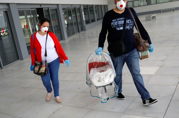 Супруги в защитных масках и с новорожденным сыном покидают больницу в городе Ронда, Испания - Sputnik Moldova