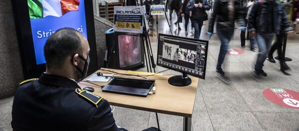 Охранник проверяет пассажиров на вокзале в Милане после этапного завершения карантина в Италии - Sputnik Moldova-România