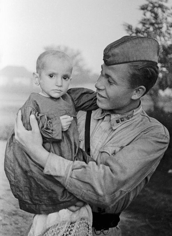 Советский офицер  держит на руках спасенную им девочку из деревни Эльхотово, 1942 год - Sputnik Moldova-România