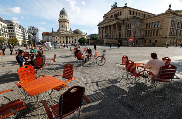 Люди наслаждаются погодой в кафе на площади Жандарменмаркт в Берлине, соблюдая принцип социальной дистанции - Sputnik Молдова