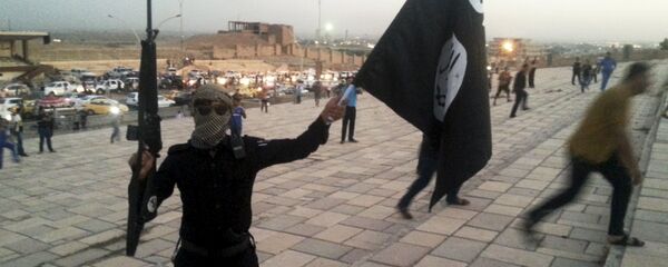 A fighter of Daesh holds an ISIL flag and a weapon on a street in the city of Mosul, Iraq, in this June 23, 2014. - Sputnik Moldova