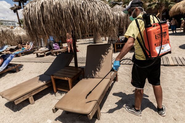 Рабочий дезинфицирует лежаки на городском пляже Алимос в пригороде Афин - Sputnik Молдова