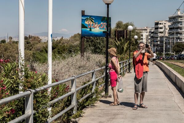 Мужчина с женщиной направляются на городской пляж Алимос в пригороде Афин - Sputnik Молдова