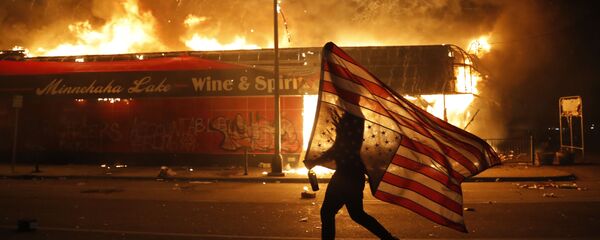 Протестующий с флагом у горящего полицейского участка в Миннеаполисе, штат Миннесота, США Протестующий с флагом у горящего полицейского участка в Миннеаполисе, штат Миннесота, США - Sputnik Moldova-România