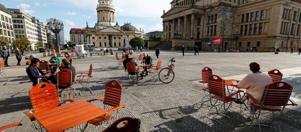 Люди наслаждаются погодой в кафе на площади Жандарменмаркт в Берлине, соблюдая принцип социальной дистанции - Sputnik Moldova