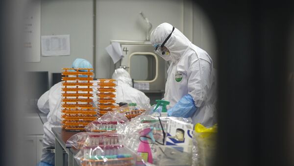 Медицинские работники в защитных костюмах в лаборатории по обнаружению коронавируса. - Sputnik Молдова