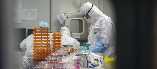 Медицинские работники в защитных костюмах в лаборатории по обнаружению коронавируса - Sputnik Moldova
