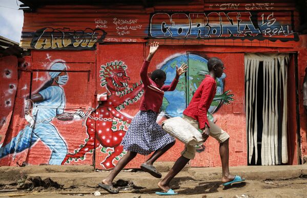 Бегущие дети на фоне посвященного коронавирусу граффити в трущобах Киберы в Найроби, Кения - Sputnik Молдова