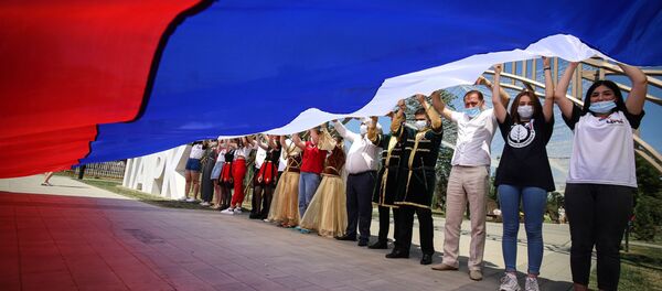 Участники празднований Дня России держат российский флаг в парке Дружбы города Георгиевска Ставропольского края - Sputnik Moldova