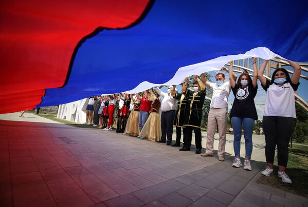 Участники празднований Дня России держат российский флаг в парке Дружбы города Георгиевска Ставропольского края - Sputnik Moldova