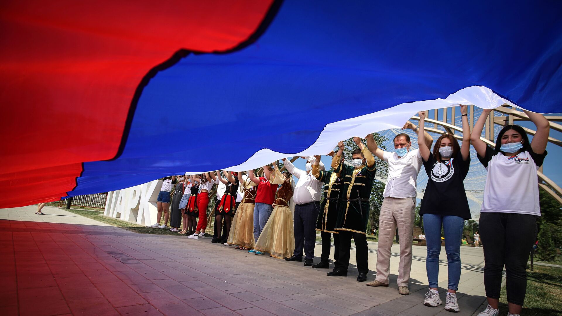 Участники празднований Дня России держат российский флаг в парке Дружбы города Георгиевска Ставропольского края - Sputnik Moldova-România, 1920, 08.04.2022