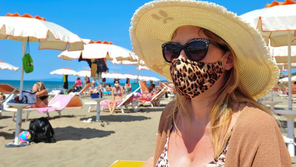 Женщина в защитной маске и солнцезащитных очках на пляже в Кастильоне-делла-Пеская, Италия - Sputnik Молдова