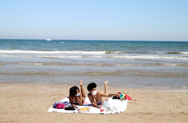 Девушки в защитных медицинских масках на пляже Malvarrosa в Валенсии, Испания - Sputnik Молдова