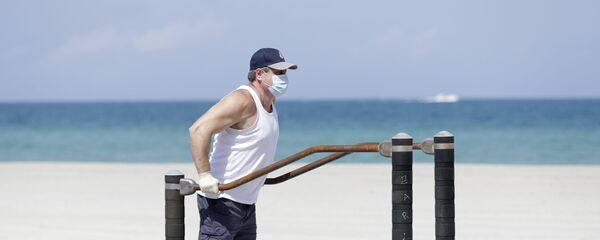 Мужчина в защитной маске во время выполнения упражнений на турнике на пляже в Голливуде, США - Sputnik Moldova
